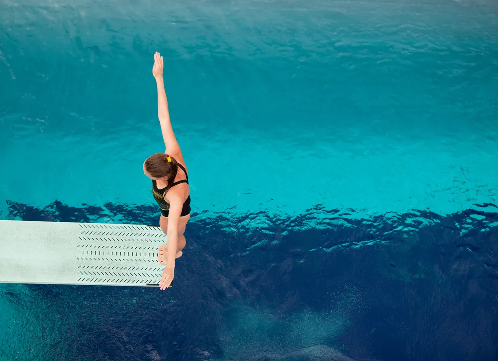 Diver on springboard above pool